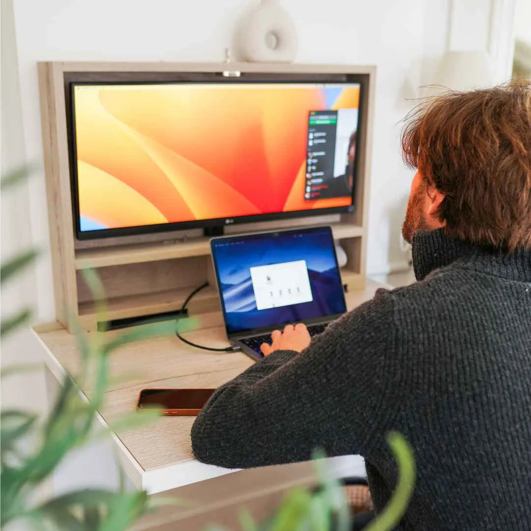 Man working at an open DropTop desk with a monitor and a laptop.