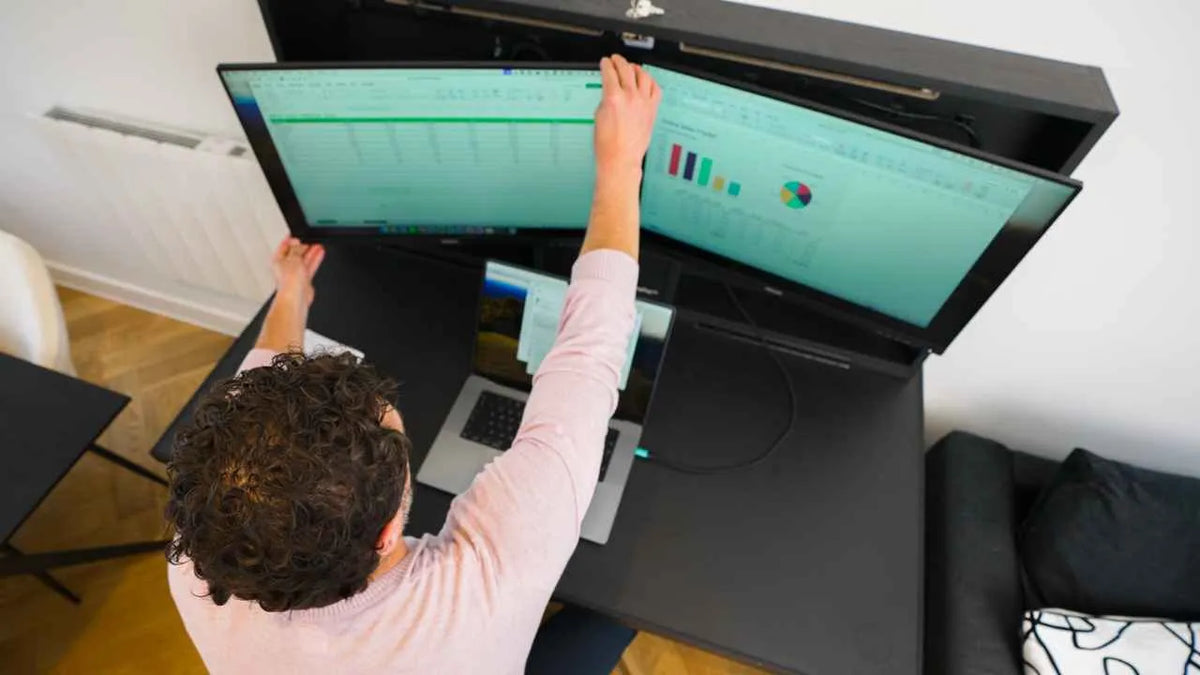 Person pulling an ultrawide monitor forward on its arm at an open DropTop desk.