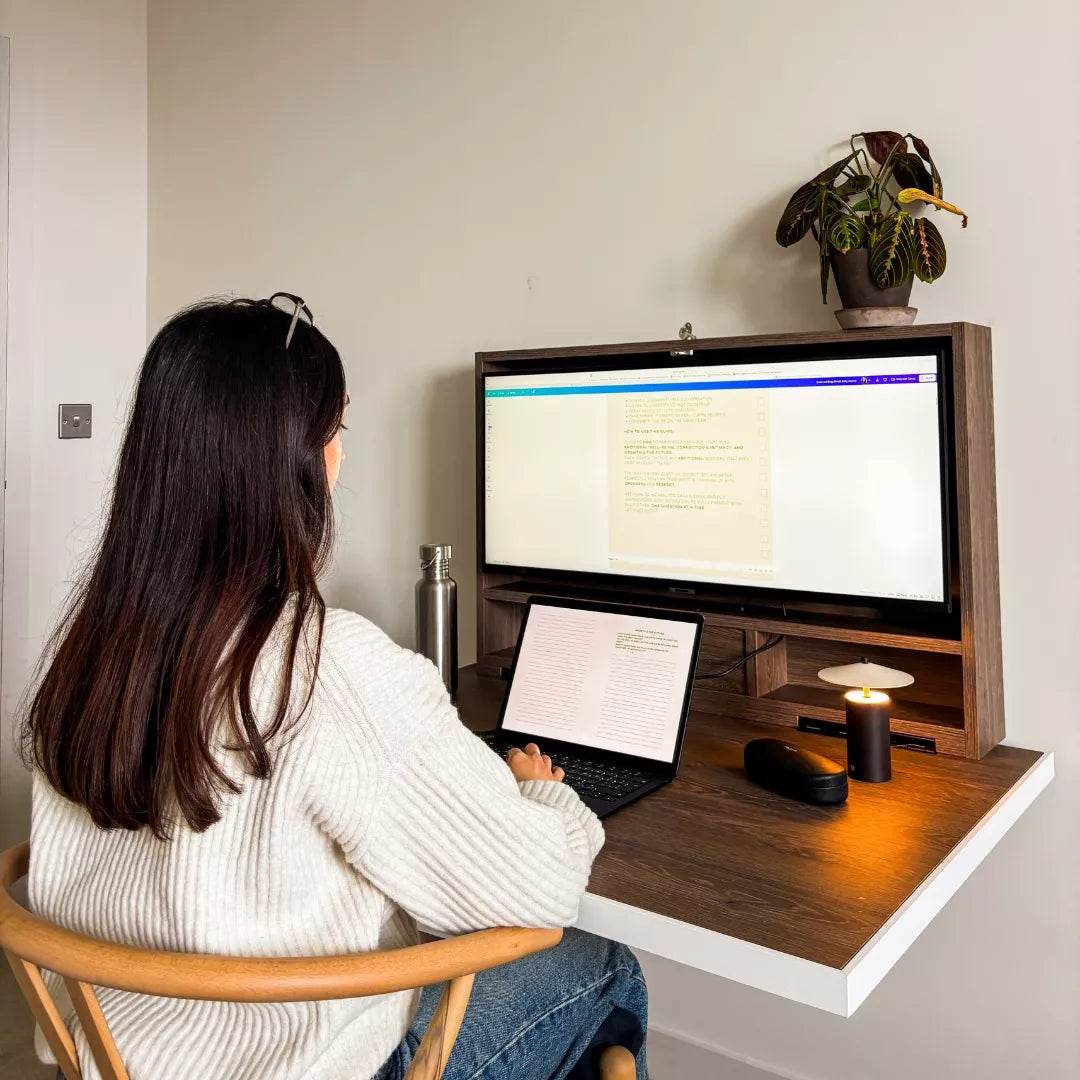 Woman working at an open dark-wood DropTop desk with an ultrawide monitor.