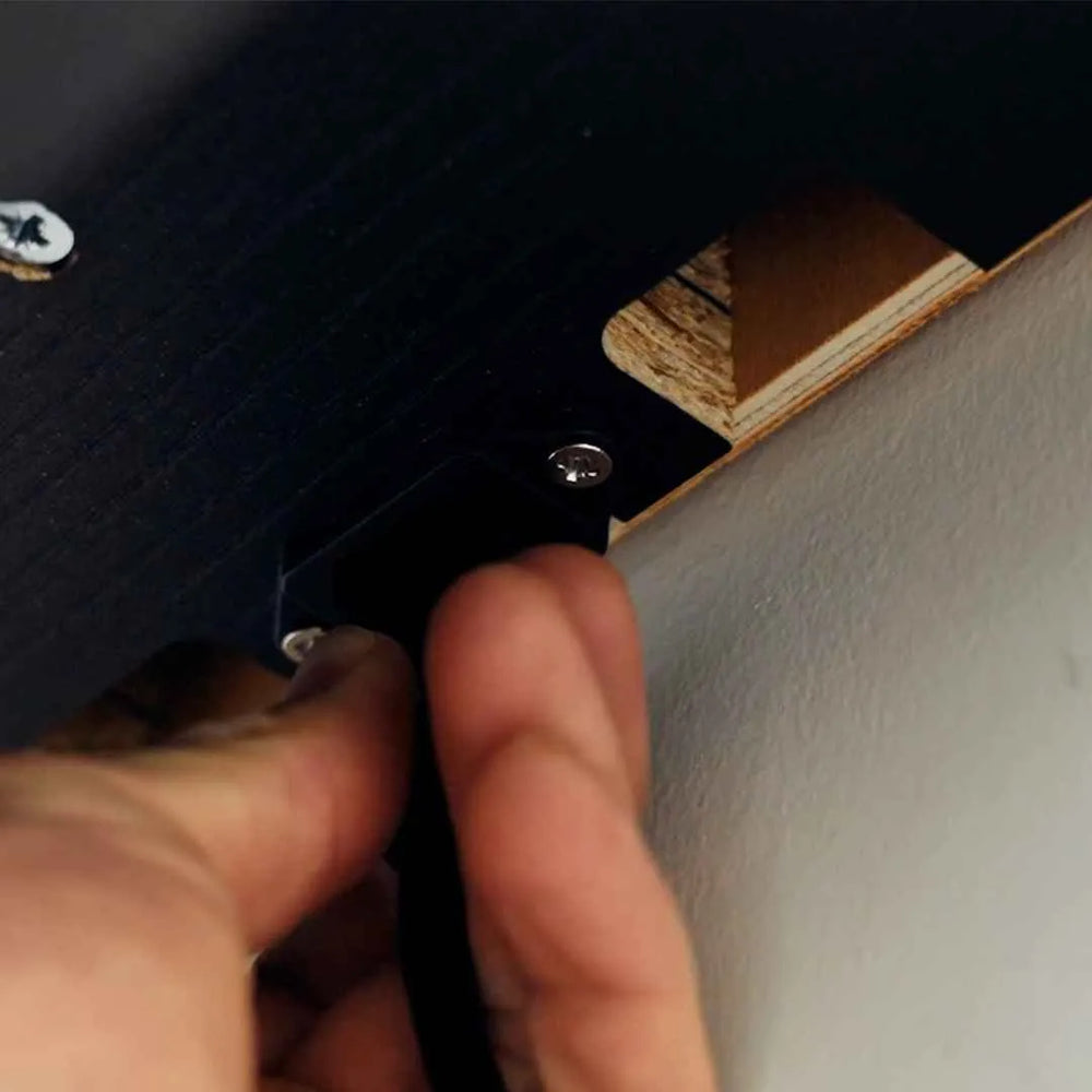 Close-up of a hand connecting the single power cable under a DropTop desk.