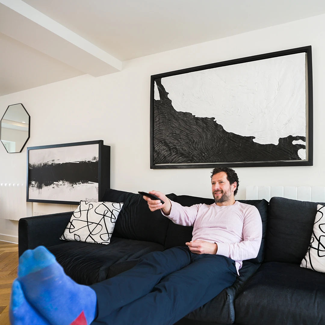 Man relaxing on a sofa beneath a closed DropTop desk displaying a large black and white print.