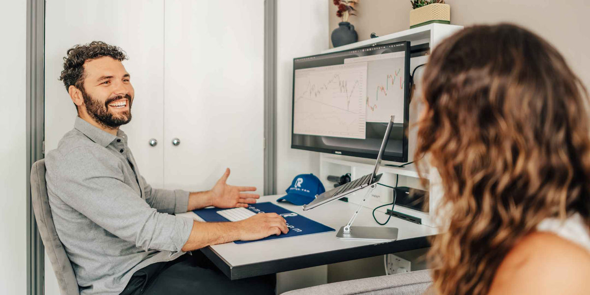 Man working at an open DropTop desk while talking to a colleague.
