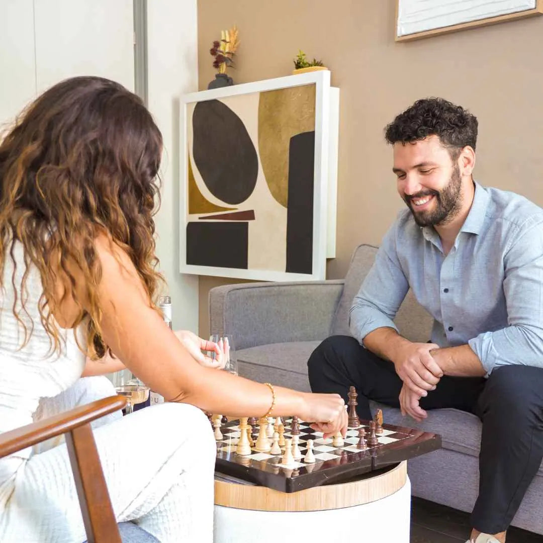 Couple playing chess on a coffee table with a closed DropTop desk behind them.