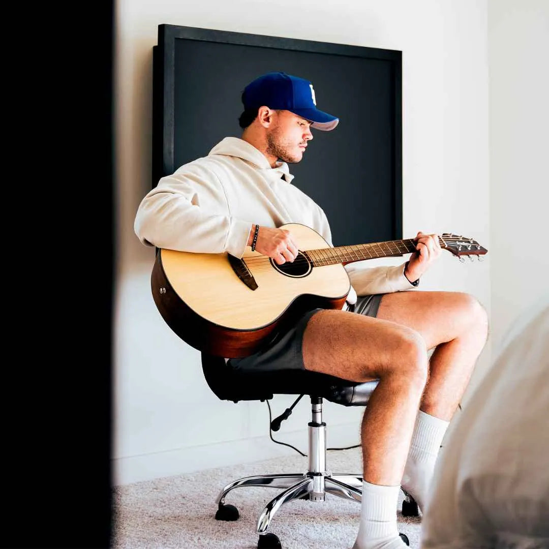 Man playing guitar in front of a closed black DropTop desk.