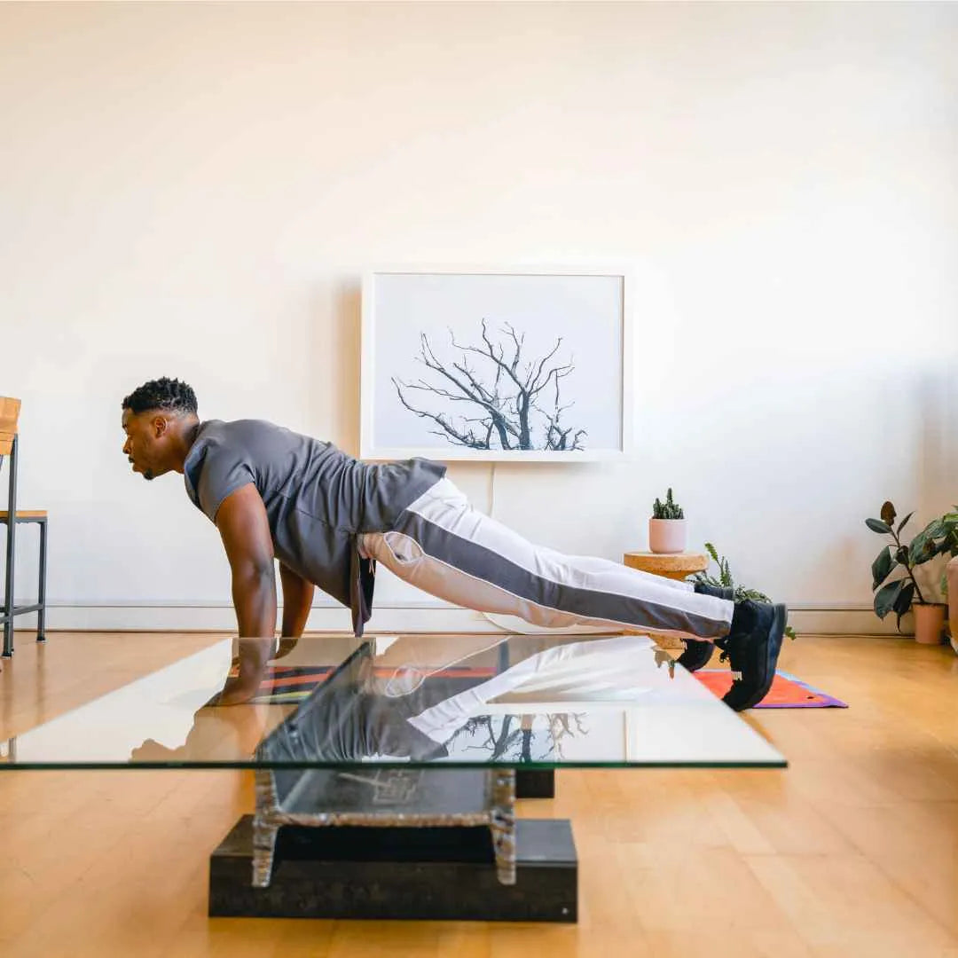 Man doing press-ups on a mat in front of a closed DropTop desk displaying a tree print.