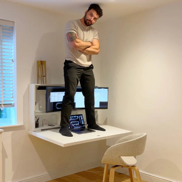 A man standing on an open DropTop desk to show its strength