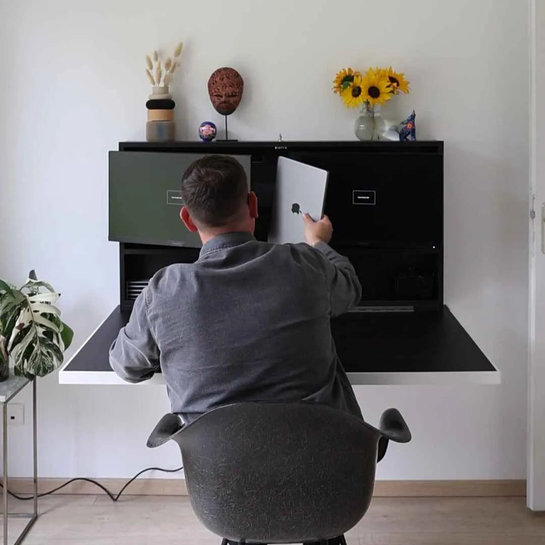 Man placing a laptop into the storage compartment of an open black DropTop Duo 24.