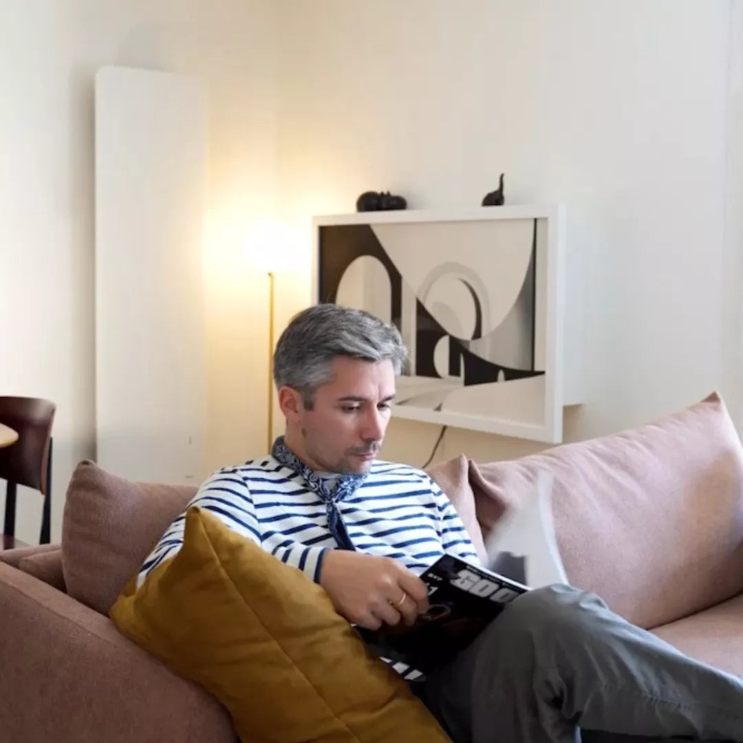 Man reading a magazine on a sofa with a closed DropTop Duo 24 on the wall behind.