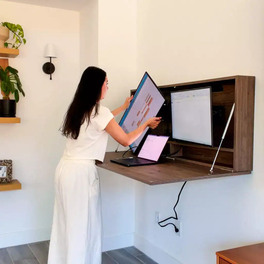 Woman adjusting one of two monitors inside an open dark-wood DropTop Duo 24 Light.