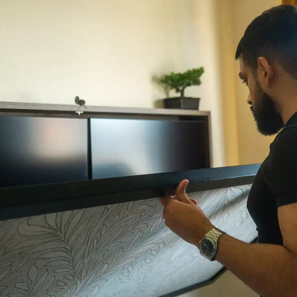 Man pulling down the desktop of a dark DropTop Duo 27 in a bedroom.