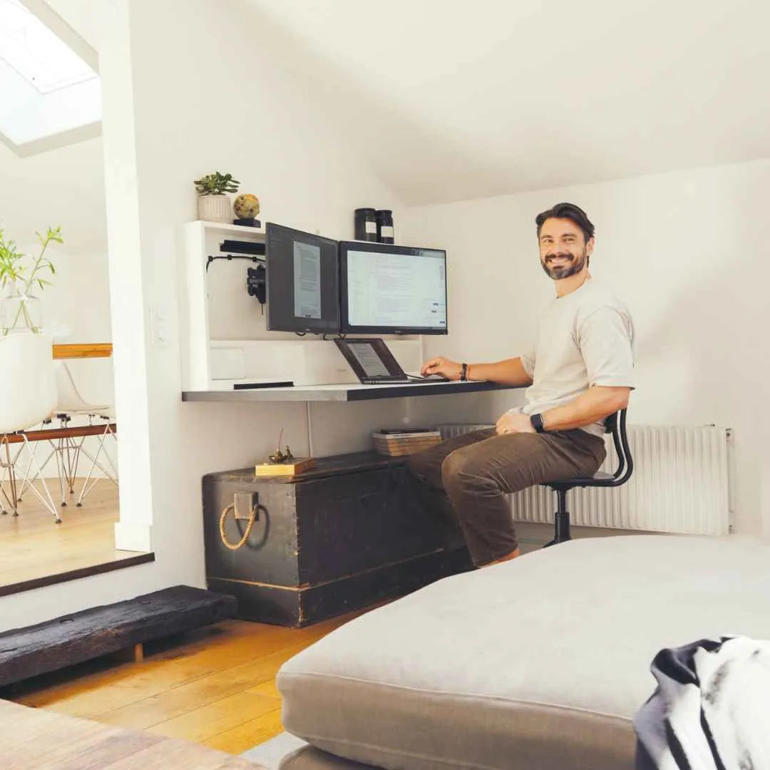 Man smiling at the camera while typing at an open white DropTop Duo 27.