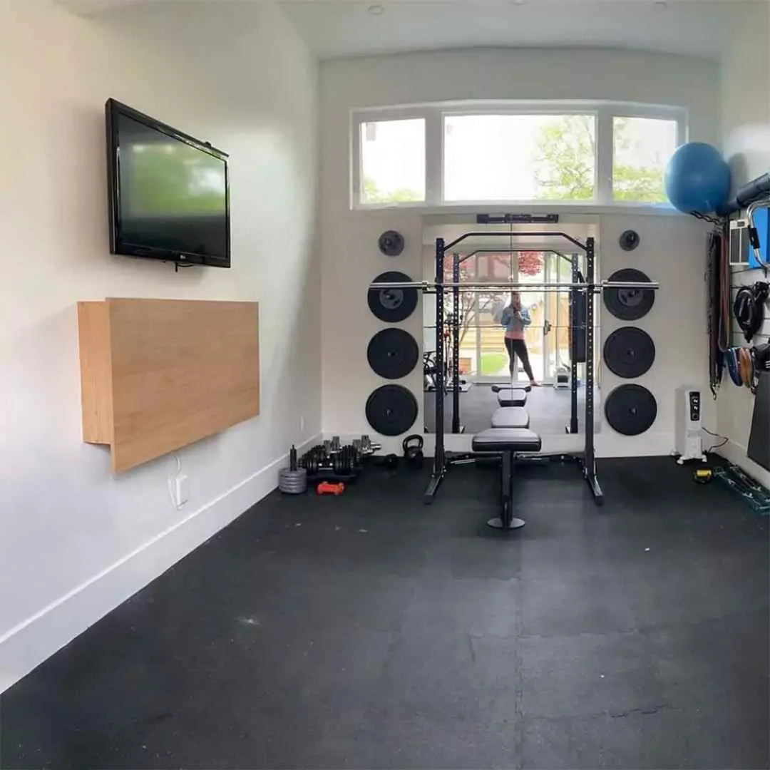 Closed oak DropTop Duo 27 Light on the wall of a home gym with a squat rack.