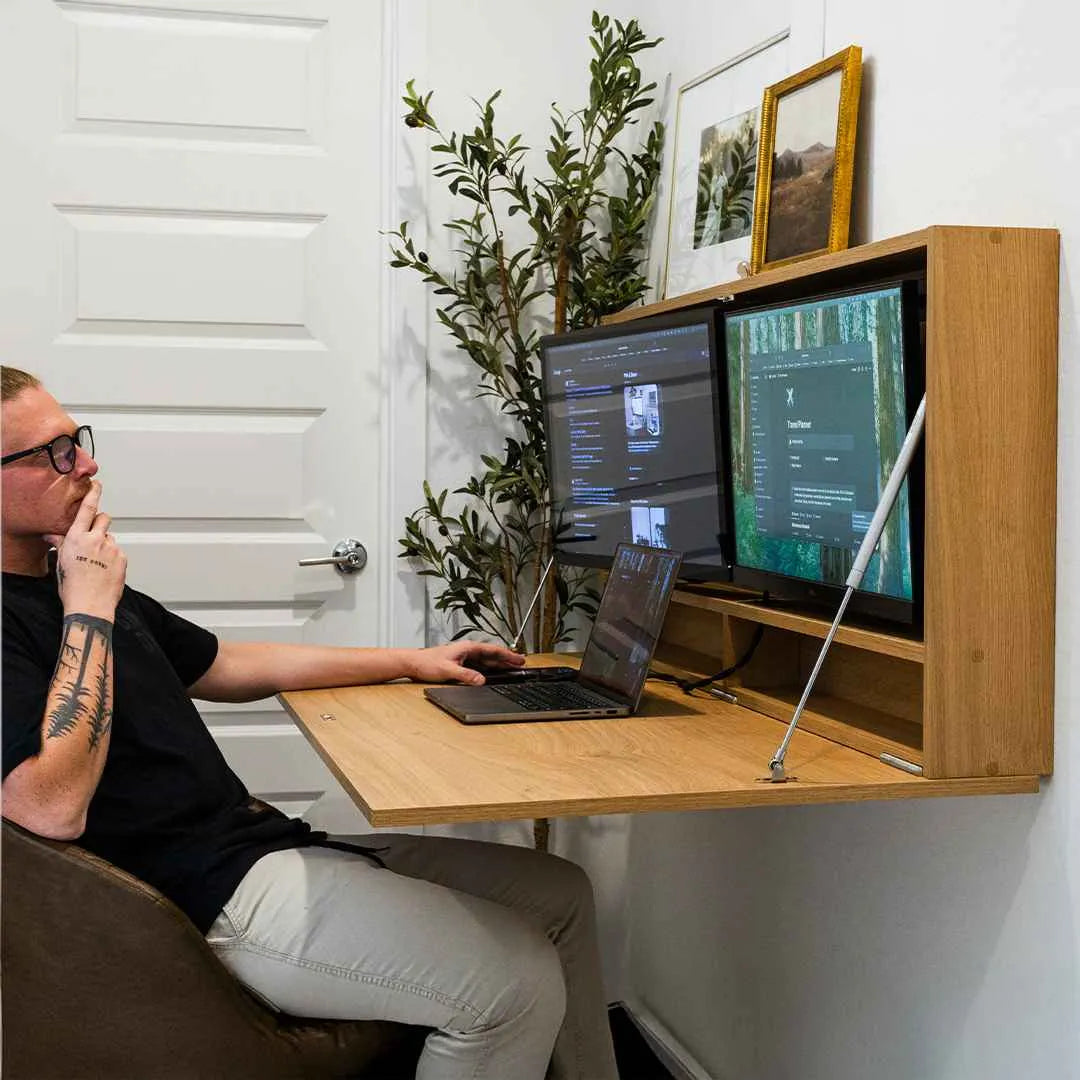 Man typing on a laptop at an open oak DropTop Duo 27 Light with two monitors.