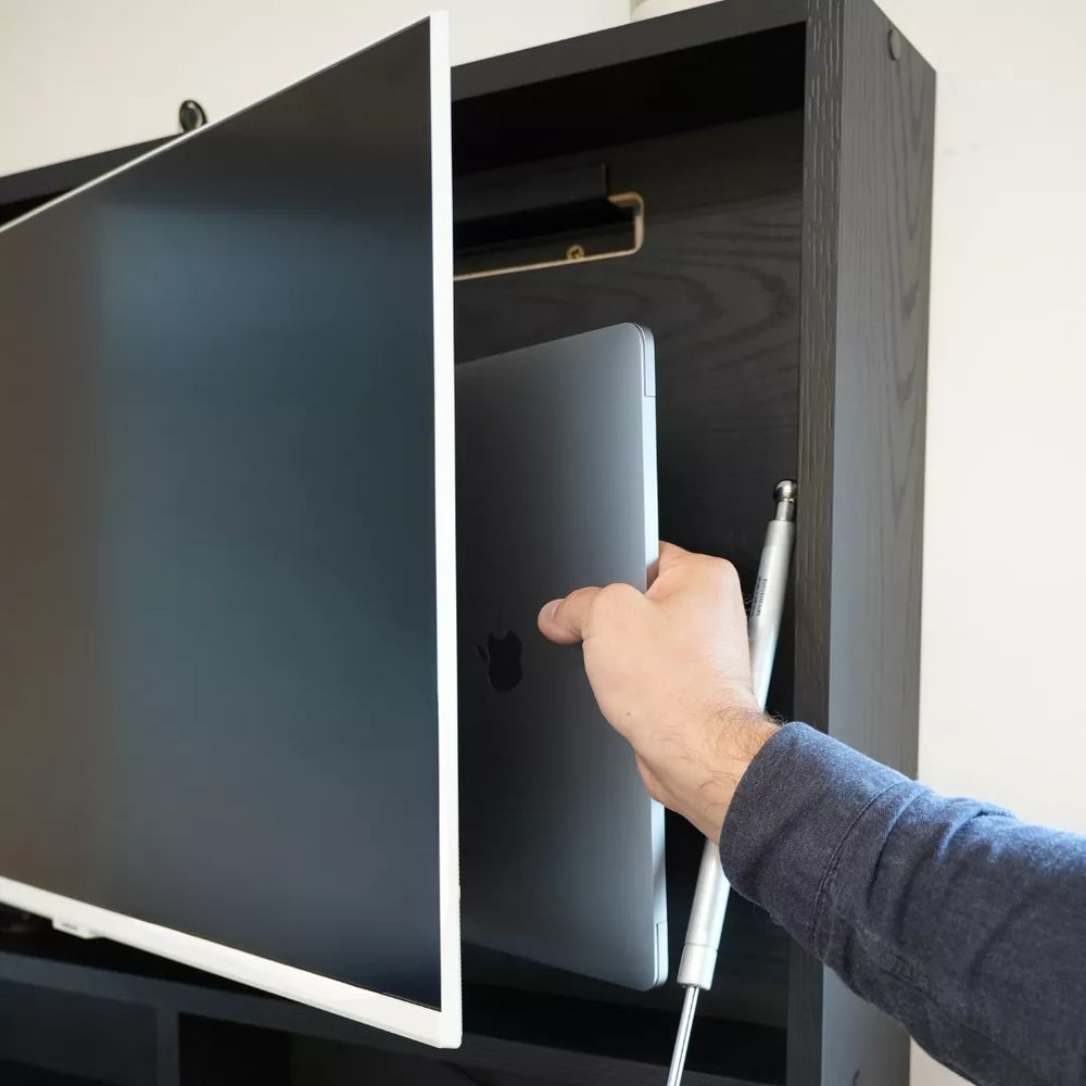Hand sliding a laptop into the storage gap behind the monitor inside a DropTop Light.