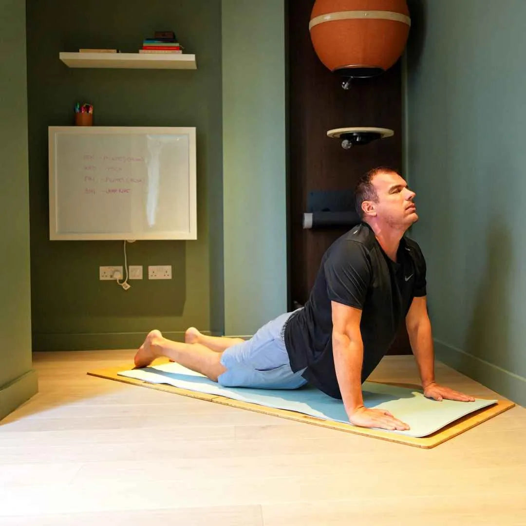 Man doing a cobra stretch on a mat in a green room with a closed DropTop Single 29.