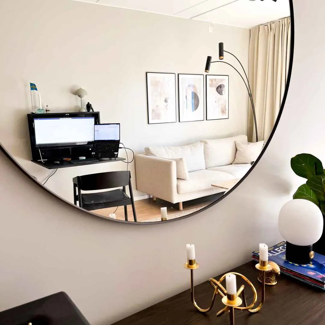 Round mirror reflecting an open black DropTop Single 29 Light with a monitor and laptop.