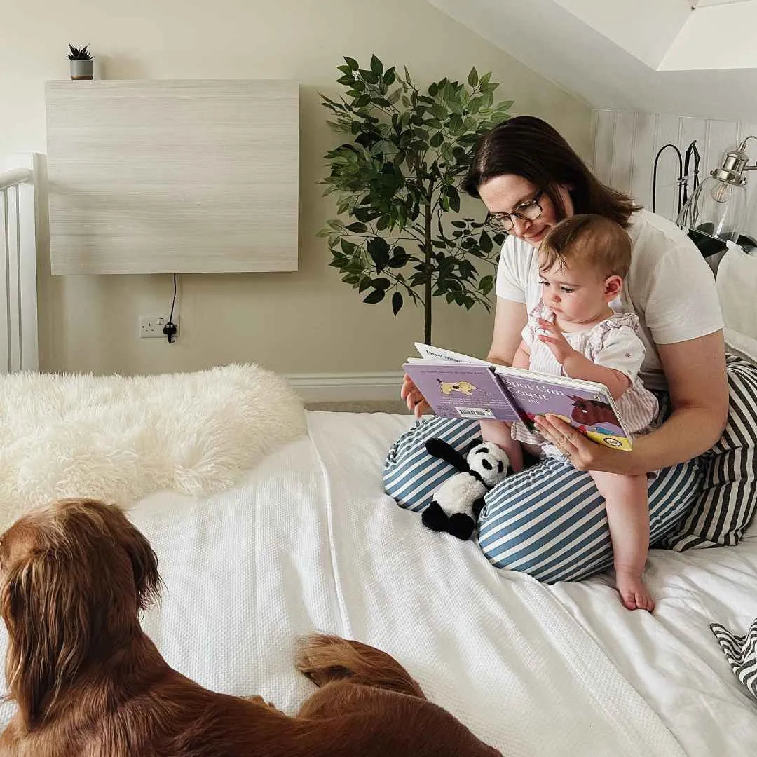 Woman reading a picture book to a baby on a bed, closed DropTop Single 34 Light behind.